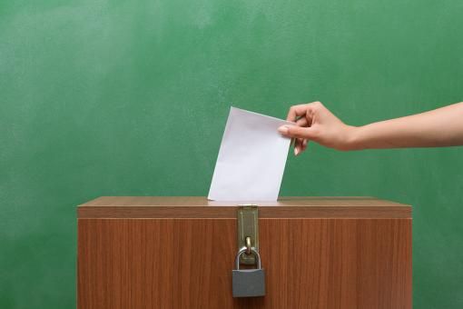 Hand inserting vote in ballot box