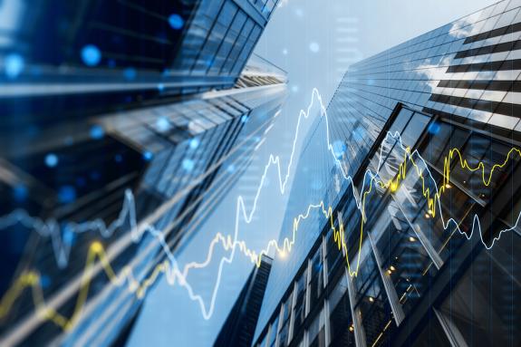 A double exposure image of skyscrapers with overlay of financial graphs, set against a blurred background.